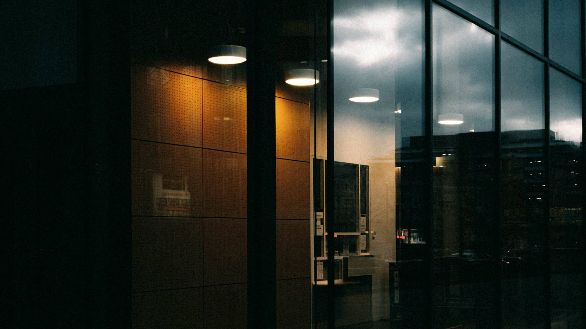 Interior de oficina iluminado con lámparas cálidas visto a través de una fachada de cristal