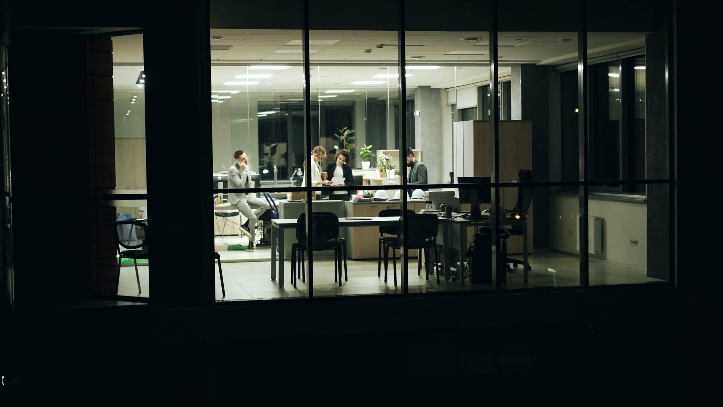 Reunión de trabajo de noche en una oficina acristalada